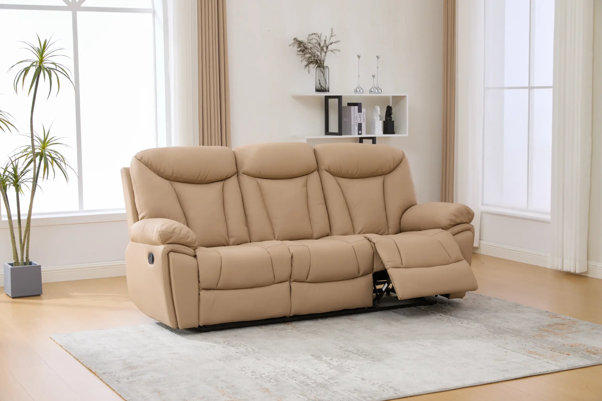 Smėlinė trivietė sofa su išskleista kojų atrama šviesioje svetainėje
